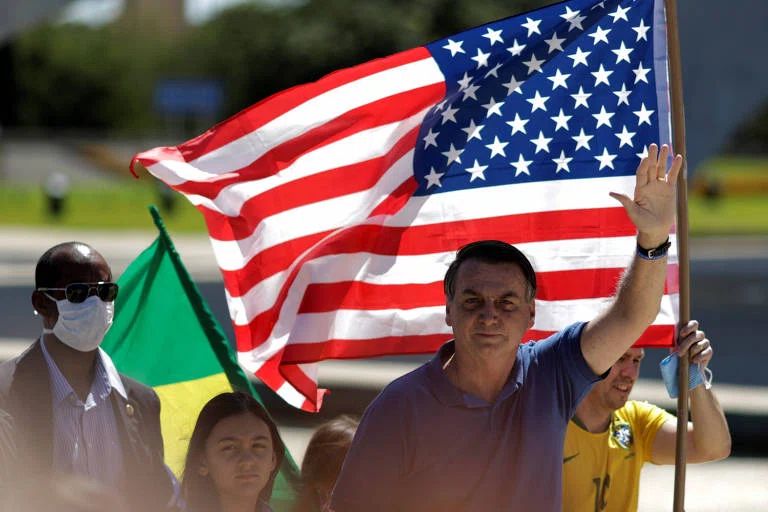 Bolsonaro, ícone da extrema direita brasileira, fazendo saudação em frente a bandeira dos EUA, Guilherme Casarões afirma que a extrema direita brasileira adapta temas do mesmo movimento dos Estados Unidos para a realidade no Brasil